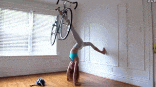 双手倒立靠墙，用脚提单车的妹子居家锻炼gif动态图片